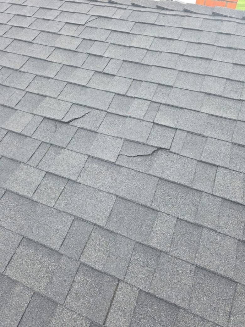 Aging composition shingle roof with cracked tabs before replacement