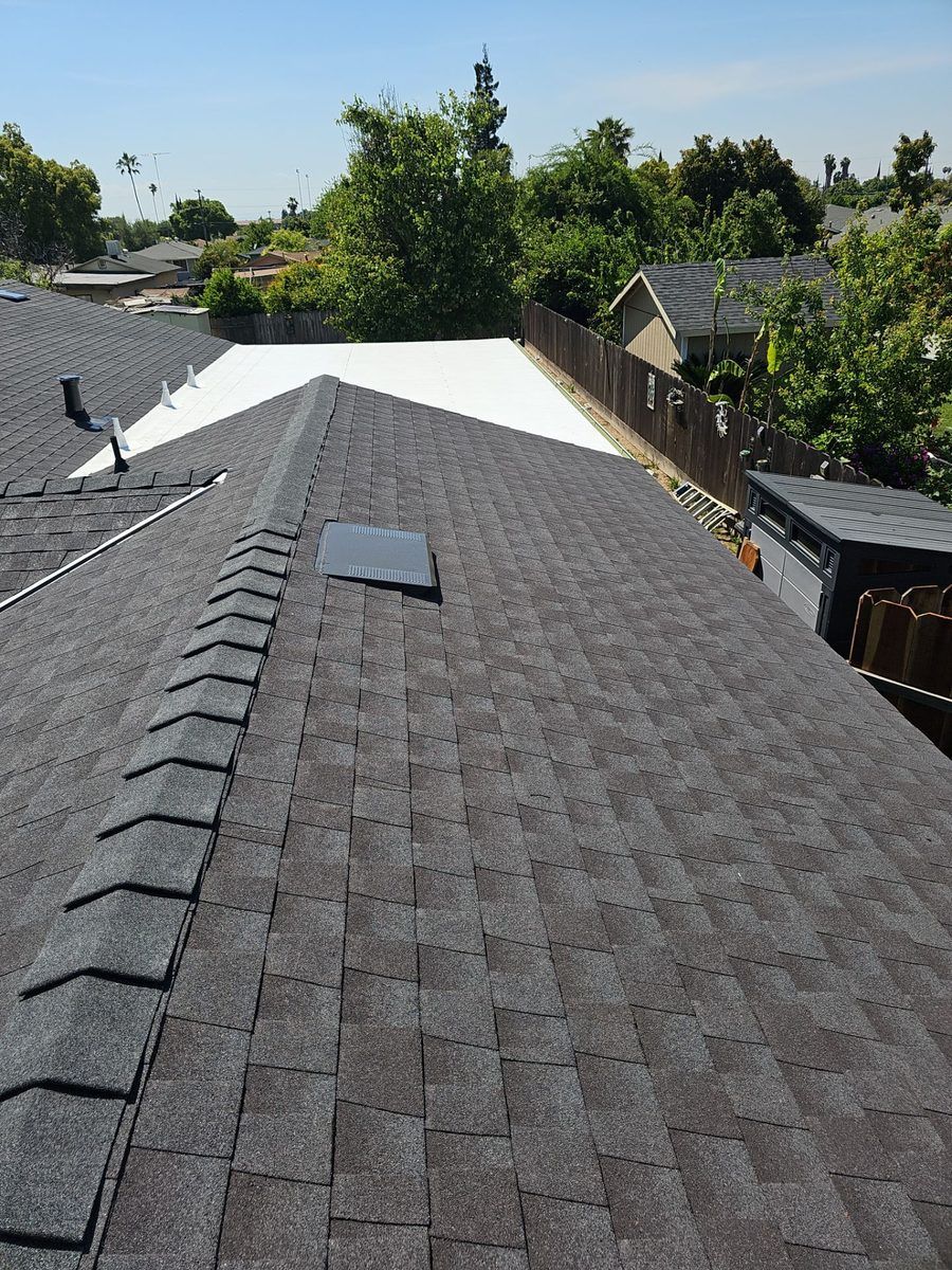 Crew working on exposed roof deck with GAF shingle bundles, complex multi-hip roof geometry