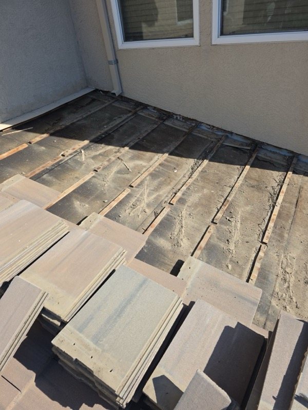 Tiles removed exposing old underlayment near wall