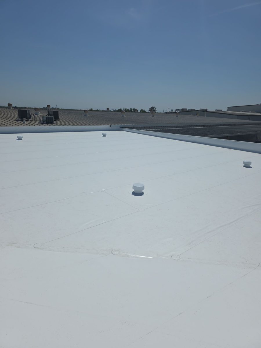 Wide roof surface showing uniform white coating across full commercial roof