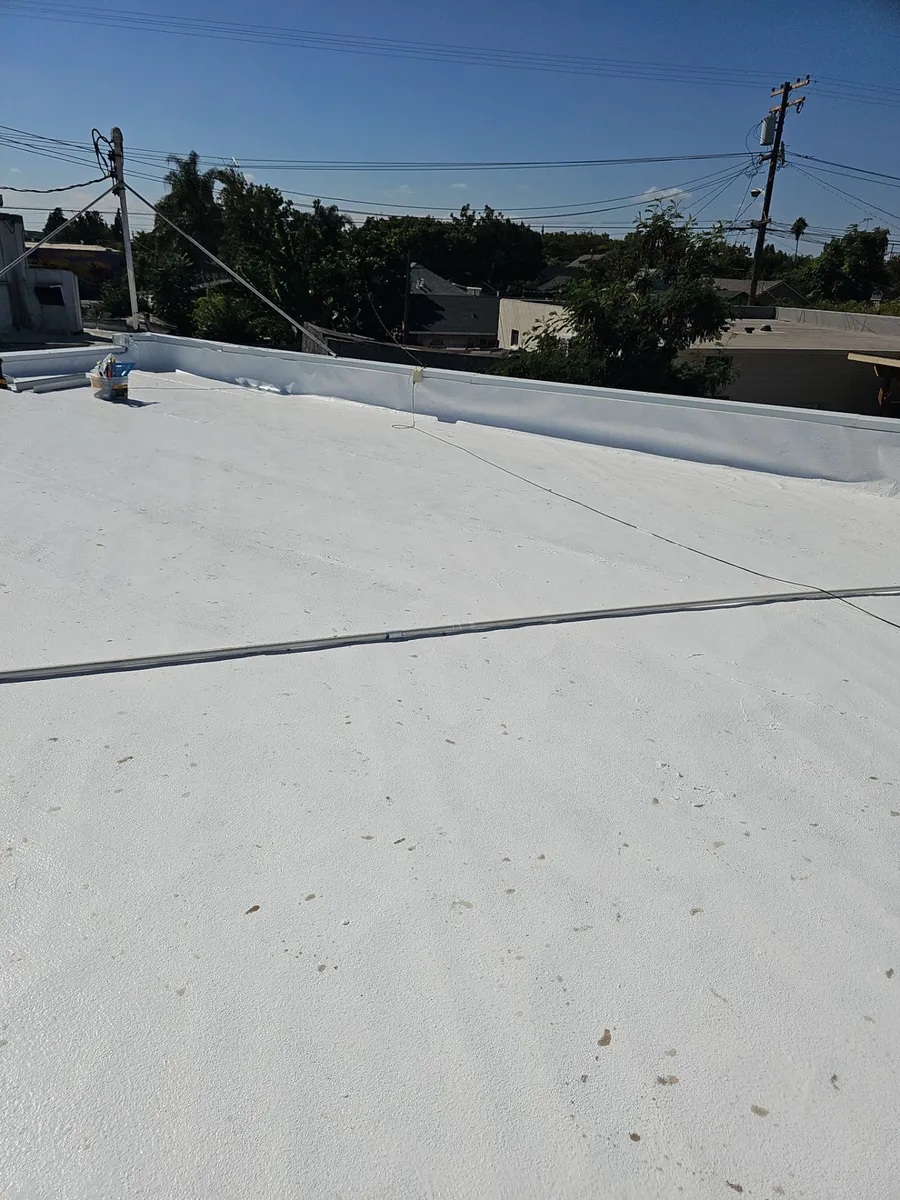 Wide view across the finished white elastomeric-coated flat roof at Beto's Bakery, Modesto