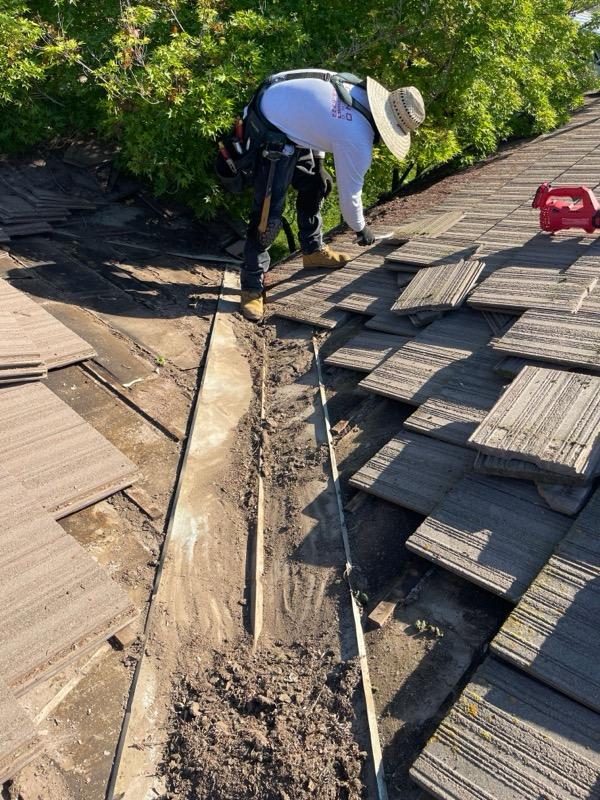 Econo Roofing crew member removing damaged concrete tiles along a roof valley in Riverbank, CA